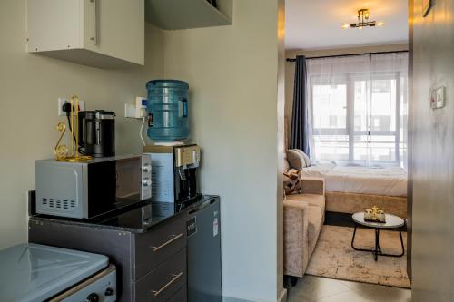 eine Küche mit einer Mikrowelle und ein Zimmer mit einem Bett in der Unterkunft Navira Studio with Pool in Nairobi