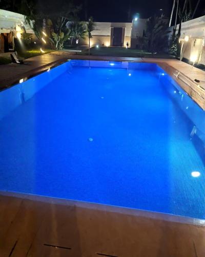 a large blue swimming pool at night at Villa Luxe Dar Bouazza - Piscine Privée - Fibre 100Mb - 3 min Plage in Casablanca