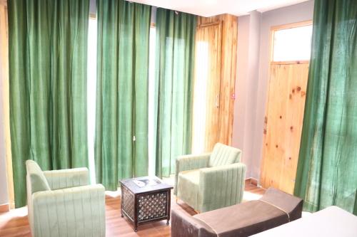 a living room with green curtains and chairs at Blest Inn Kasol in Jāmb