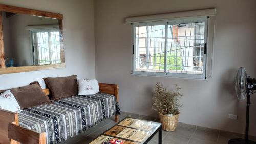 Una sala de estar con un sofá y una ventana. en Apart Fincas de San Pablo II, en Deán Funes