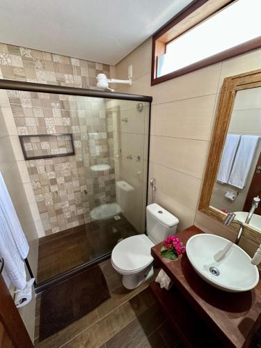 a bathroom with a toilet and a shower and a sink at Arraia Suítes Pousada in Pipa