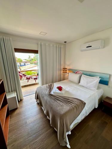 a bedroom with a large bed and a large window at Arraia Suítes Pousada in Pipa