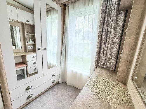 Stunning 8 Berth Caravan With Decking At Kessingland Beach Ref 90017D في Benacre: غرفة مع نافذة ومقعد بجوار باب