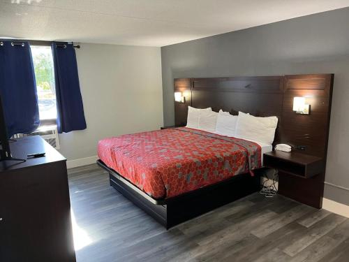 a hotel room with a bed with a red bedspread at Roseville Inn in Roseville