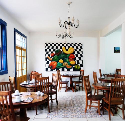 a dining room with tables and a painting of fruits at Tiradentes Pousada Ramalhete in Tiradentes