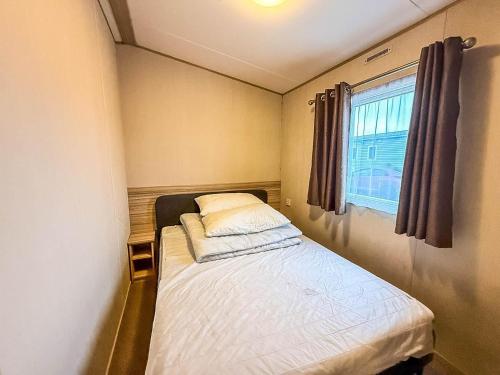 a small bed in a small room with a window at 6 Berth Caravan With Side Decking At Suffolk Sands Holiday Park Ref 45054C in Felixstowe