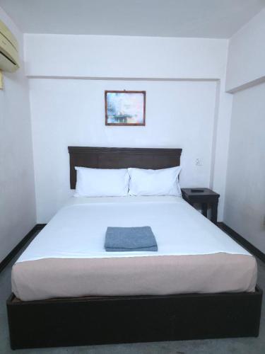 a bedroom with a white bed with a blue towel on it at Hotel Bumimas in Kuantan