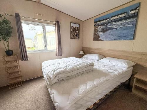 Cosy 6 Berth Caravan With Side Decking At Kessingland Beach, Suffolk Ref 90031Sv في Benacre: غرفة نوم بسرير كبير ونافذة