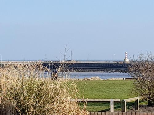 een brug over een rivier met een vuurtoren op de achtergrond bij Wheelhouse 21 in Amble