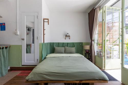 ホーチミン・シティにあるKibou Homestayの緑のヘッドボードが付いた大きなベッドのある寝室