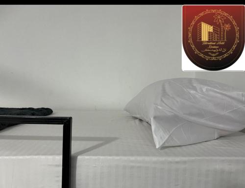 a bed with a white pillow and a sign on it at international hoste in Muscat
