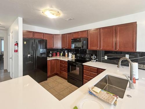 een keuken met houten kasten en een zwarte koelkast bij Canyon View Oasis home in Redlands