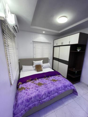 1 dormitorio con 1 cama grande con sábanas moradas en Spacious one bed self compound, en Iju Junction