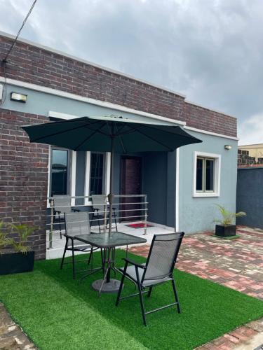 Un patio con una mesa y sillas y una sombrilla. en Spacious one bed self compound, en Iju Junction