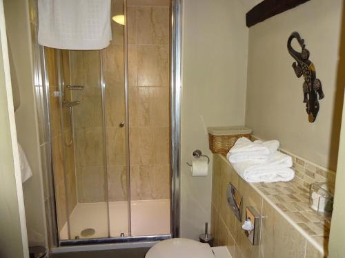a bathroom with a shower and a toilet and towels at The Cross Keys in Saffron Walden