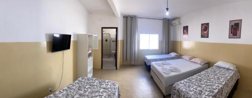 a small room with two beds and a television at Pousada Aconchegante in Jequié