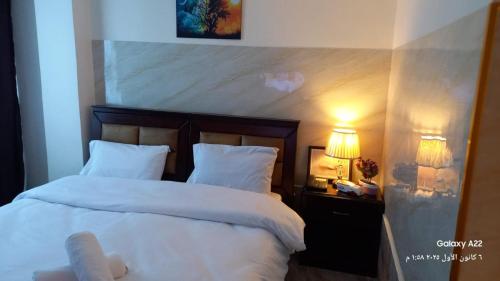 un dormitorio con una cama con sábanas y almohadas blancas en Kahraman Amman Hotel, en Amán