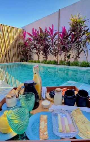 圣米格尔-杜戈斯托苏Pousada Villa di Luna的游泳池旁边有一张桌子上摆着盘子和花瓶