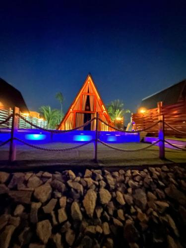 un edificio in legno con luci blu di notte di LIMMAT Chalés a Hora