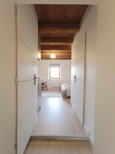 Un pasillo que conduce a un dormitorio con paredes blancas y techos de madera. en Le Parmelan - Sur la route d'Annecy, en Alby