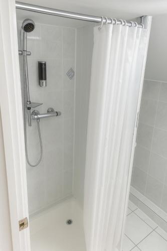 a shower with a shower curtain in a bathroom at shabi inn in Ilford