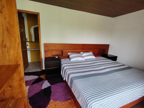 Homestay Natural Paradise habitación 3 في سان كريستوبال: غرفة نوم بسرير كبير مع لوح رأس خشبي