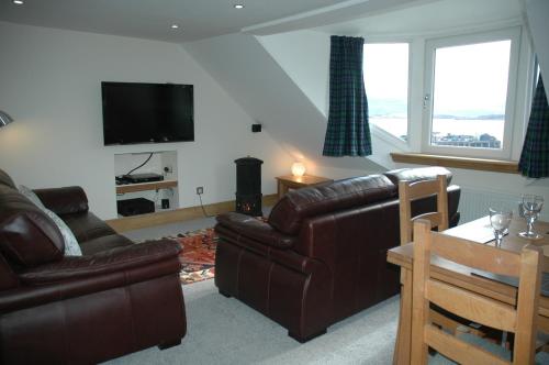 a living room with a leather couch and a television at Harbourside in Tobermory