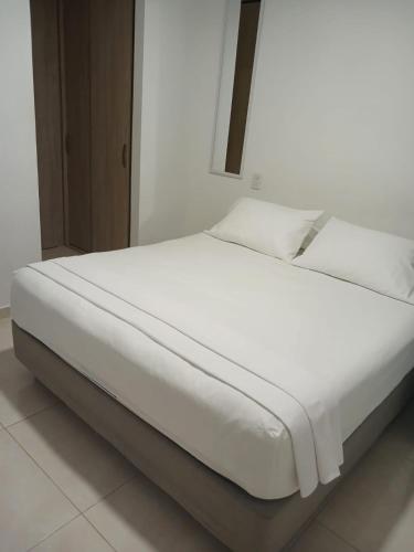 Jardin imperial, habitaciones para tu disfrute y descanso en apto familiar في كارتاهينا دي اندياس: سرير بشرشف ووسائد بيضاء في الغرفة