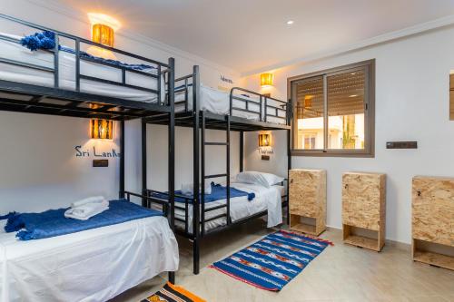 een kamer met 2 stapelbedden en 2 stoelen bij Nomazigh Surf House in Tamraght Ouzdar