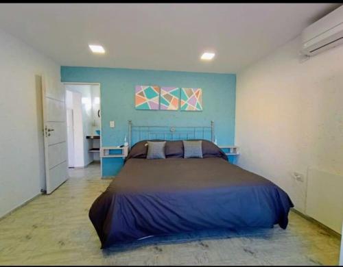 a bedroom with a bed and a blue wall at Atardeceres del dique in Cortaderas