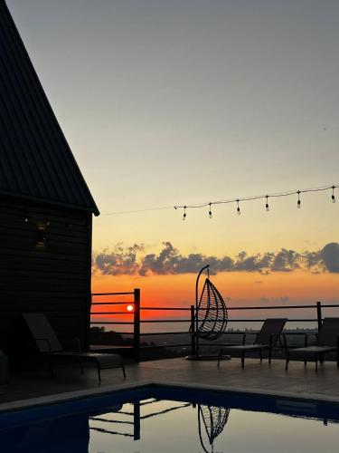 a sunset over a swimming pool with chairs and a swing at Kvirike Hills Hotel in Kobuleti