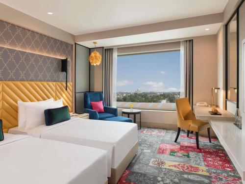 a hotel room with a bed and a desk and a window at Grand Mercure Agra - An Accor Brand in Agra