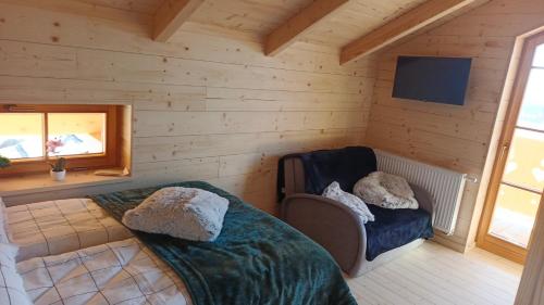 Domki pod łanem في تيلسز: غرفة بسرير وكرسي وتلفزيون