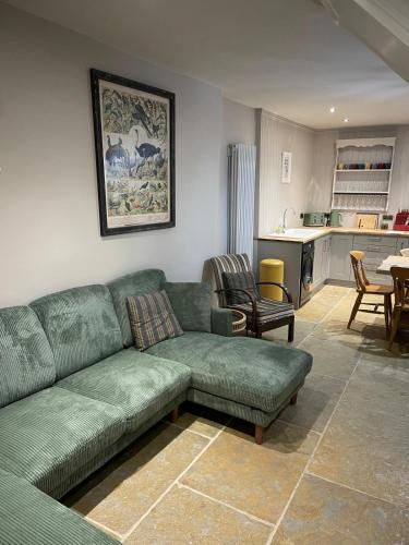 a living room with a green couch and a kitchen at The Merchants Barn - A New Unique Town Centre Home in King's Lynn