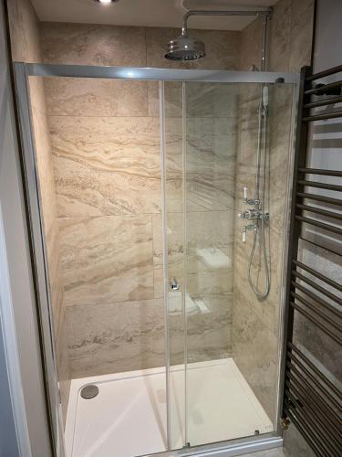 a shower with a glass door in a bathroom at The Merchants Barn - A New Unique Town Centre Home in King's Lynn