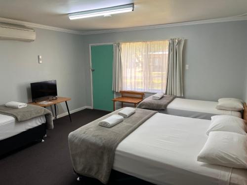 Una habitación de hotel con dos camas y un televisor. en Restawile Motel, en Busselton