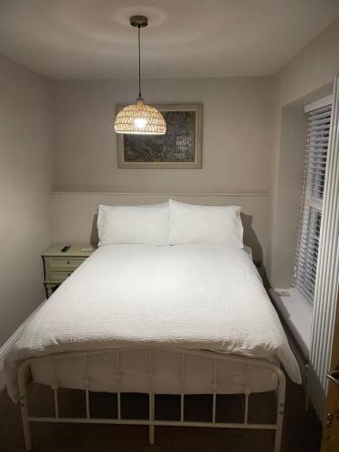 a bedroom with a white bed with a chandelier at The Merchants Barn - A New Unique Town Centre Home in King's Lynn