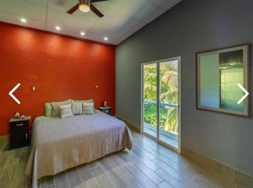 een slaapkamer met een bed en een rode muur bij Casas Héctor Rios in Yelapa