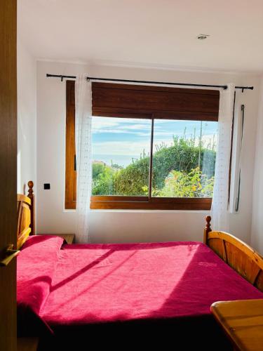 a bedroom with a red bed and a window at House with ocean and mountain views in Santa Susanna