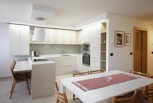a kitchen with white cabinets and a table and chairs at CASA BEBA - Cavalese Olimpiadi 2026 Dolomiti Affitti in Cavalese