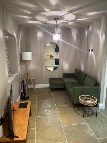 a living room with a green couch and a mirror at Bishops Keep - A New Unique Town Centre Home in King's Lynn