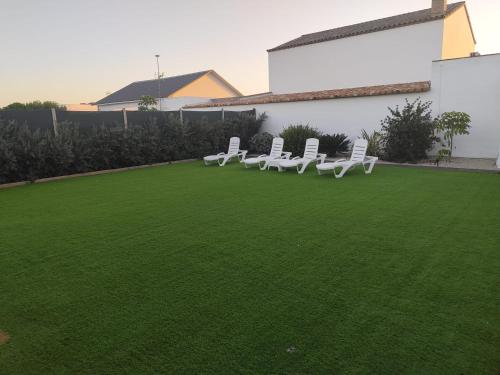 a row of white chairs sitting on a lawn at Casa Olas y Arena el Palmar in El Palmar