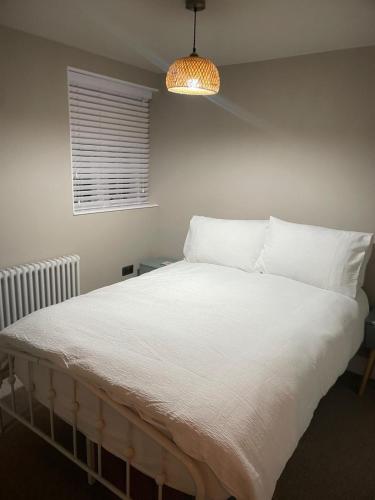 a bedroom with a bed with white sheets and a lamp at Bishops Keep - A New Unique Town Centre Home in King's Lynn