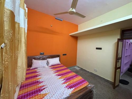 Bett in einem Zimmer mit orangefarbener Wand in der Unterkunft Siva Sandhy Guset House in Tiruvannāmalai
