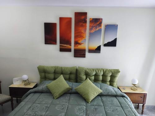a bedroom with a bed with four paintings on the wall at Franca la Sarta House in Castellana Grotte