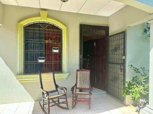 Habitación León Queen Deluxe في ليون: كرسيين جالسين على الشرفة الأمامية للمنزل