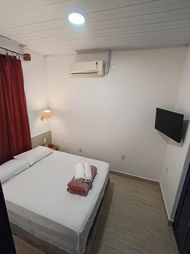 安达拉伊Pousada e Hostel Andarai的卧室里有一张白色的床和一台平板电视