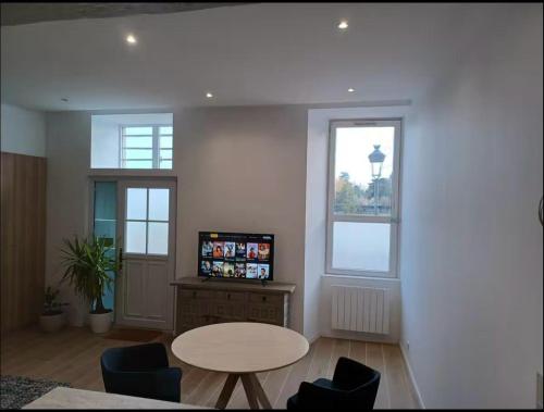 a living room with a table and two windows at Superbe 2 pièces refait à neuf idéalement situé in Meung-sur-Loire
