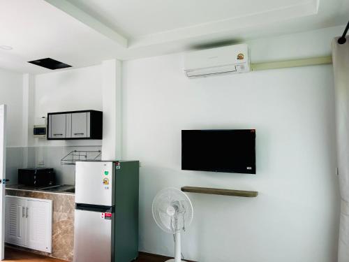 una cucina con frigorifero e una TV a parete di Sarona House 4 a Ban Thalat Choeng Thale