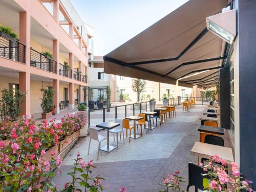 an outdoor patio with tables and chairs and flowers at B&B Hotel Roma Tuscolana San Giovanni in Rome